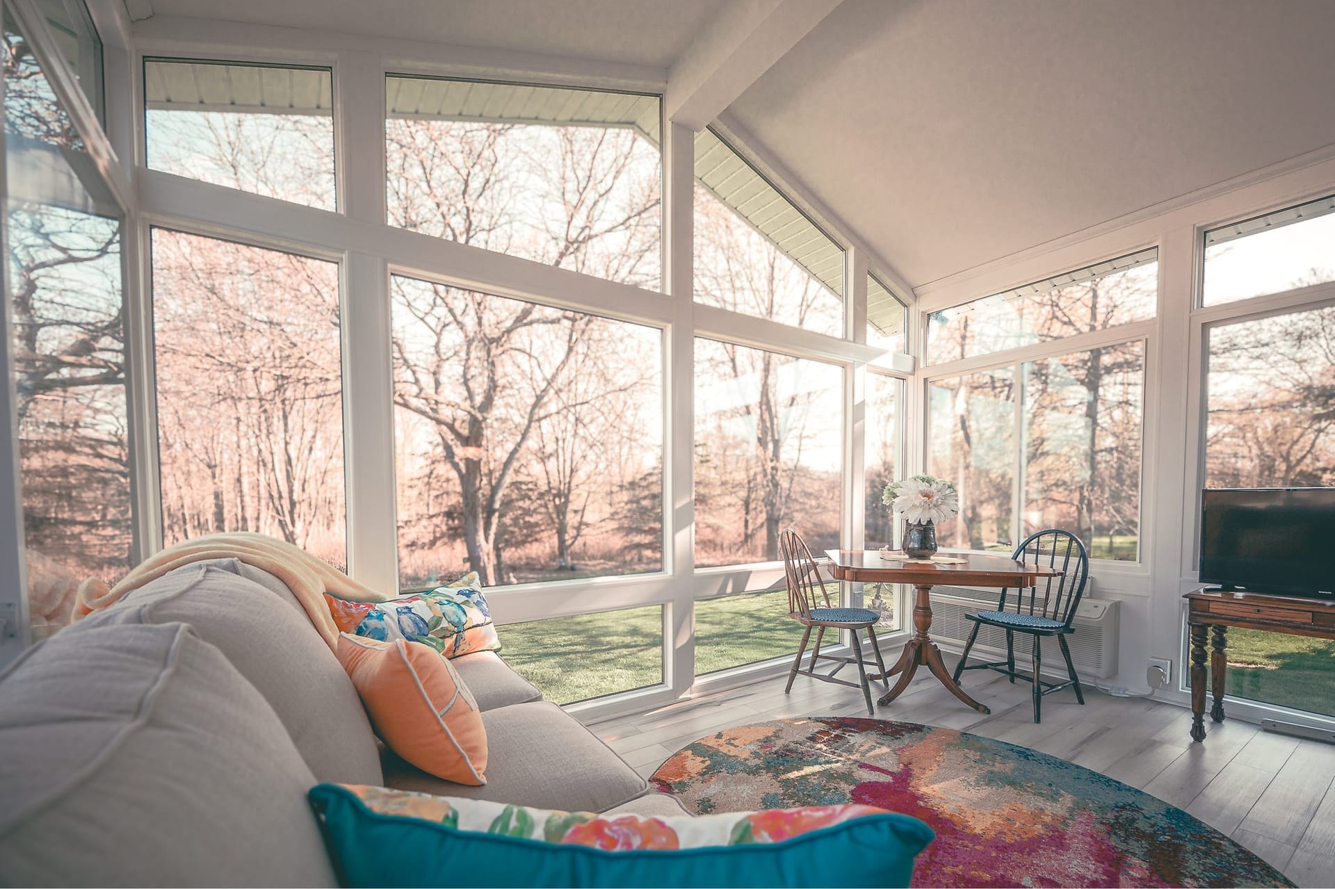 Soft-lit LivingSpace sunroom interior with morning light and outdoor living project brochures on a coffee table