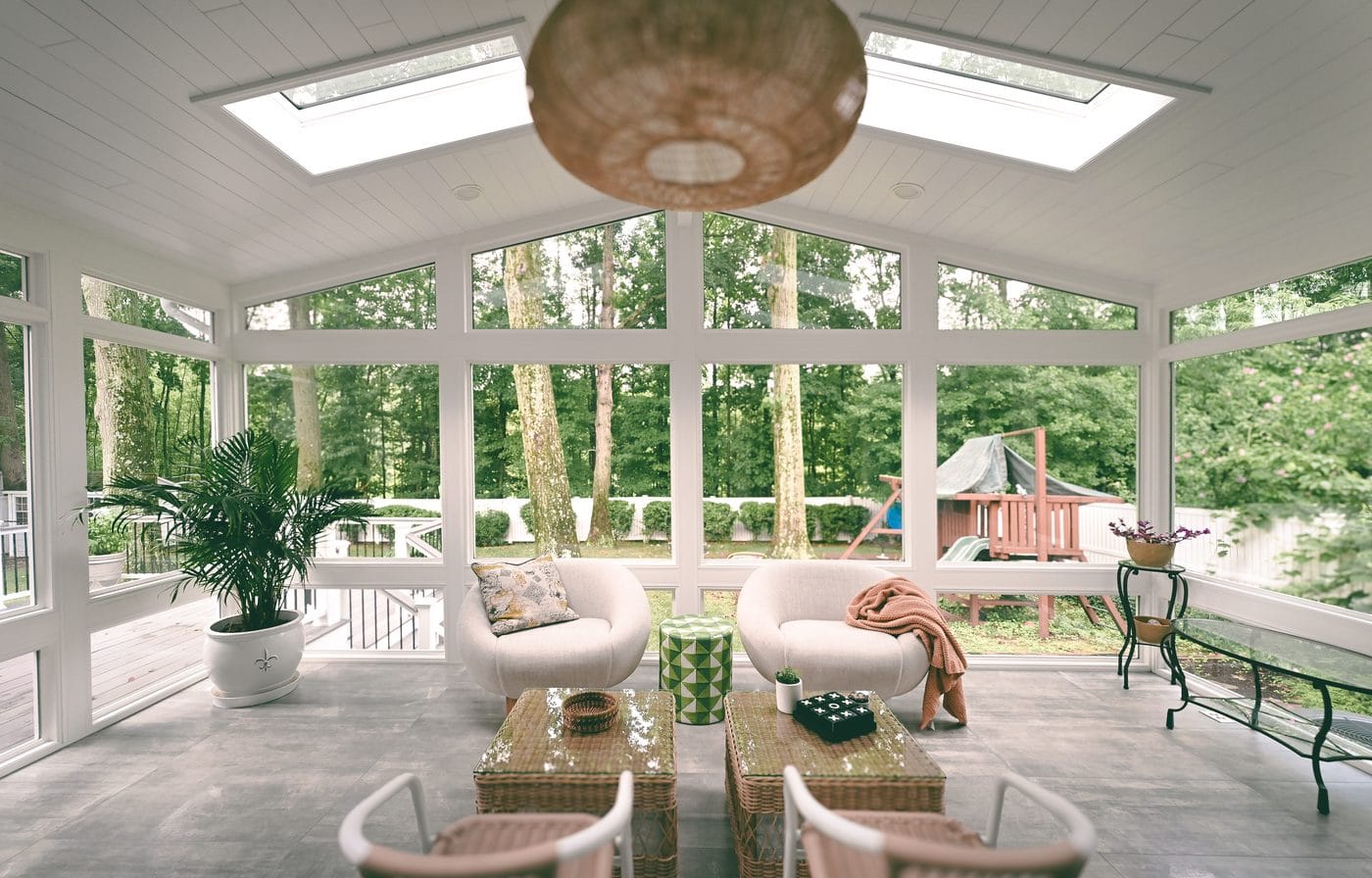 Bright sunroom interior with woven seating and skylights overlooking a wooded South Jersey backyard
